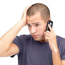 Man grimacing while holding phone to ear Man grimacing while holding phone to ear